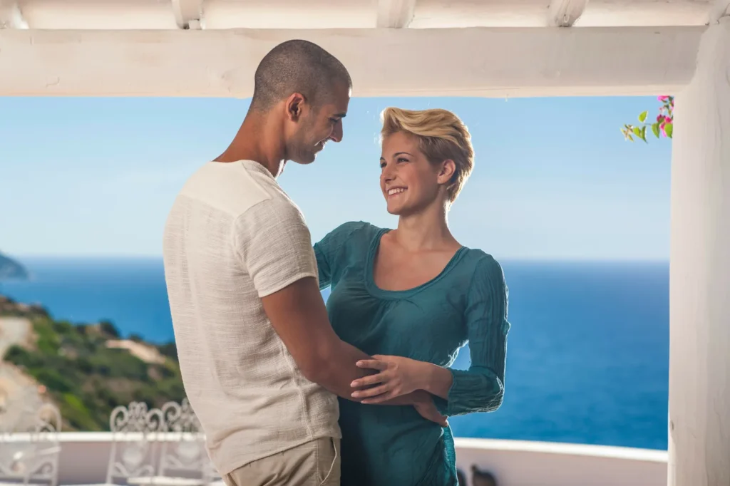 Paar auf einem überdachten Balkon mit Blick auf das Meer
