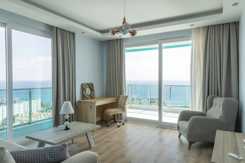 Helles möbliertes Wohnzimmer mit großen Fenstern und Balkon mit Meerblick